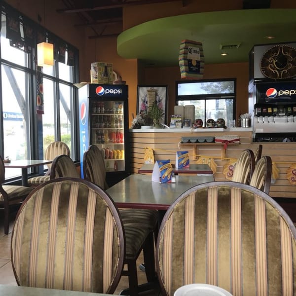 Interior of Mami's Mexican Grill with tables, chairs, Pepsi coolers, and Mexican-themed decor.
