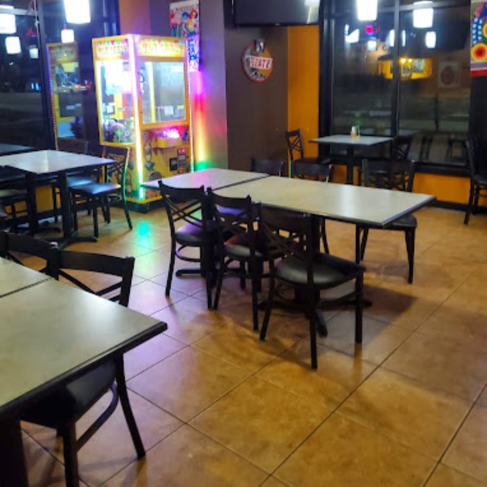 Interior of Mami's Mexican Grill with empty tables, chairs, and claw machines in the background.
