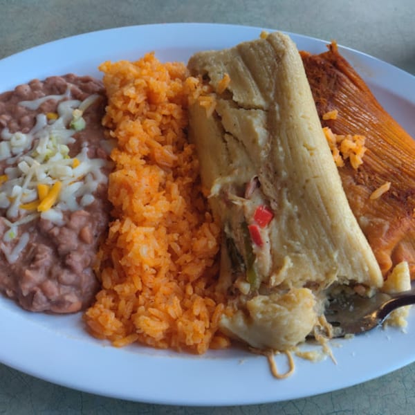 A plate of Mami's Mexican Grill tamales, refried beans with cheese, and orange rice.