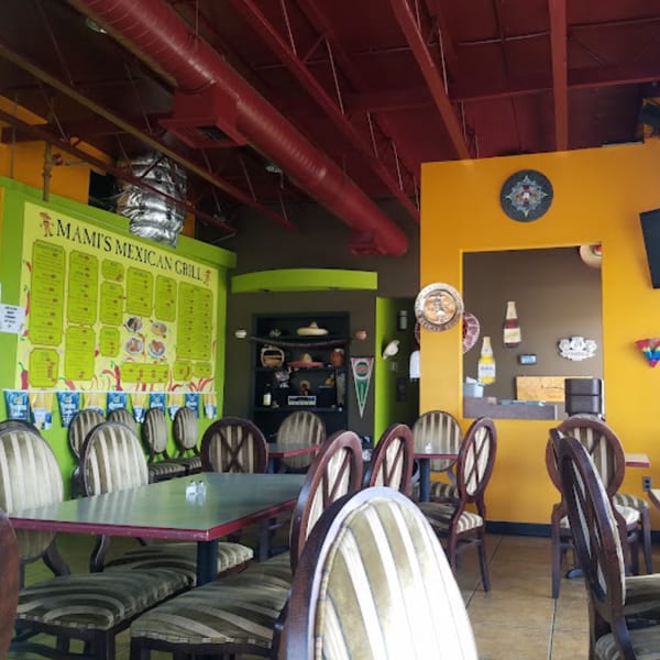 Interior of Mami's Mexican Grill with colorful walls, tables, chairs, and a large menu board.